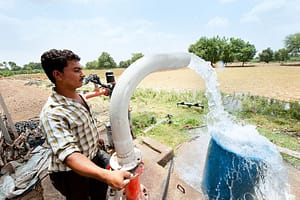 Man operating a electric motor pump in his plantation. Photo: Hamish John Appleby / IWMI