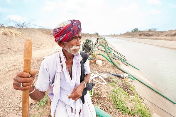 Farmer in Gujarat looks on as irrigation pumps and pipes pull water from the canal for farms Farmer in Gujarat looks on as irrigation pumps and pipes pull water from the canal for farms