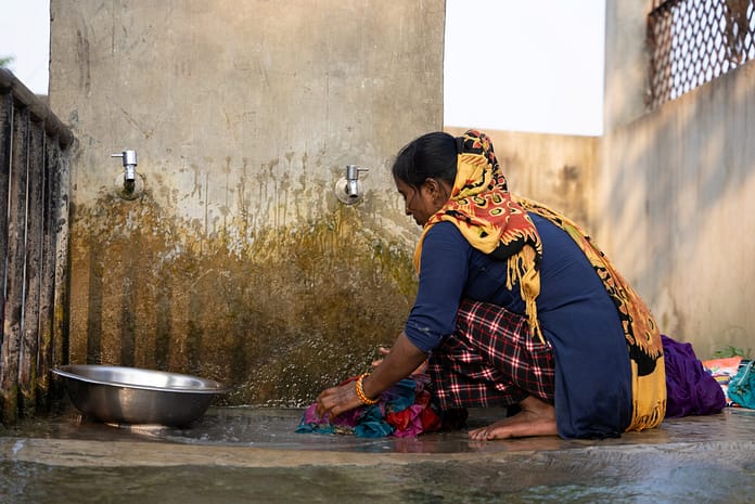In Sarlahi district, Nepal a woman washes clothes at a communal water source. Climate-related hazards and extreme weather events disrupt WASH services, particularly impacting rural households, where water storage systems are frequently insufficient. Photo: SDG Studio for IWMI