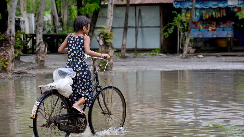 A girl rides a bicycle through a flood road in Mandalay, Myanmar. Photo: Anirut Thailand/Shutterstock