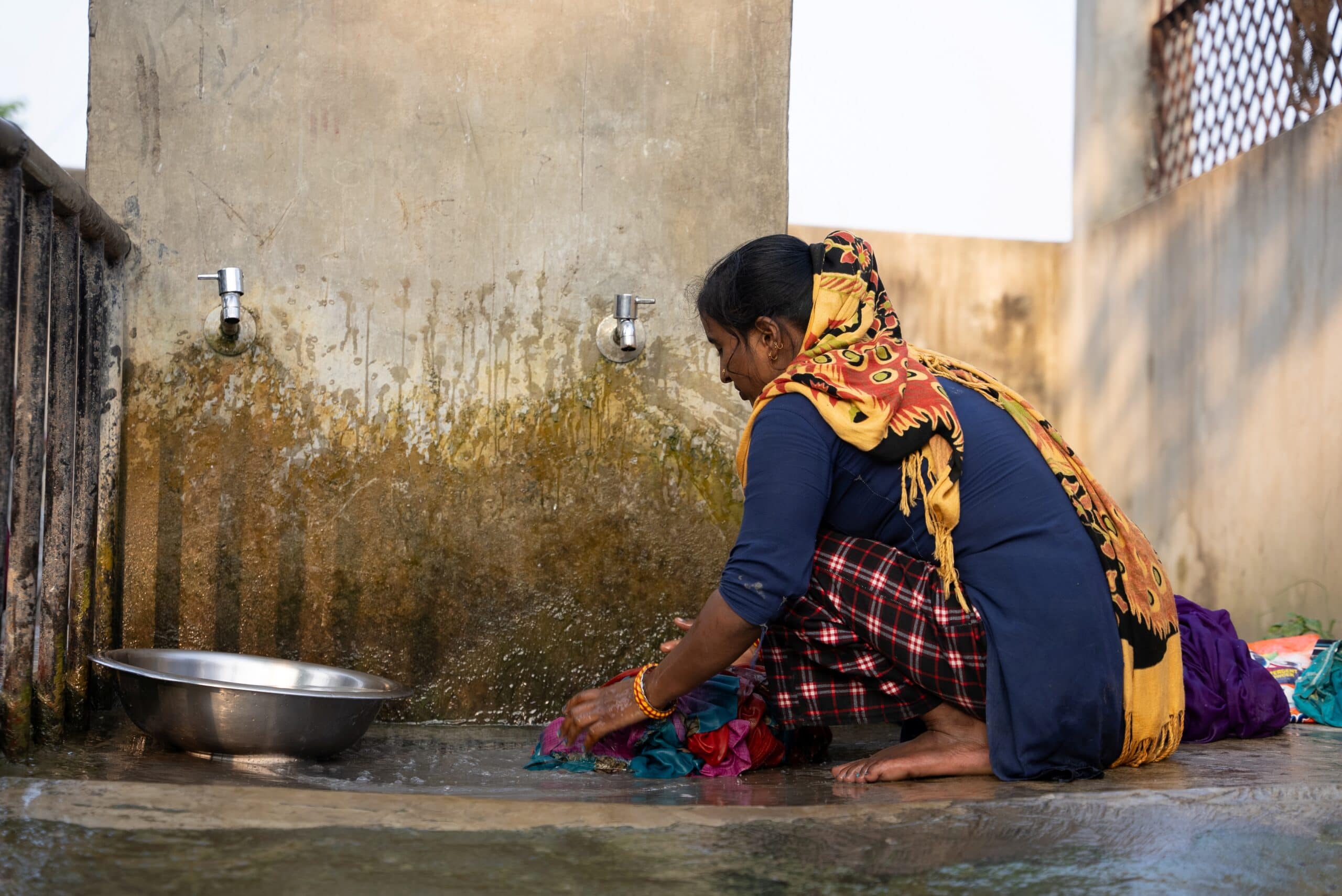 In Sarlahi district, Nepal a woman washes clothes at a communal water source. Climate-related hazards and extreme weather events disrupt WASH services, particularly impacting rural households, where water storage systems are frequently insufficient. Photo: SDG Studio for IWMI