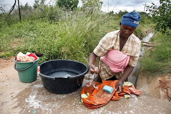 A woman washing clothes on canal bridge