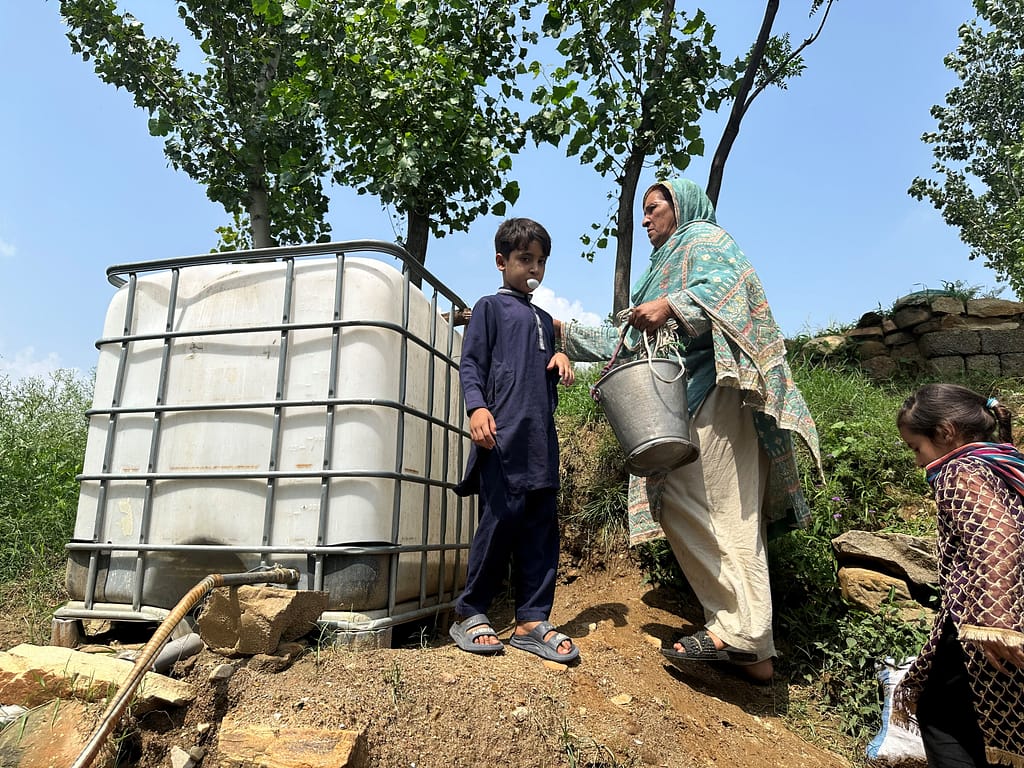 A resident collects water from a storage tank supplied by the hydraulic ram pump system in the village. Photo: Amjad Jamal/IWMI