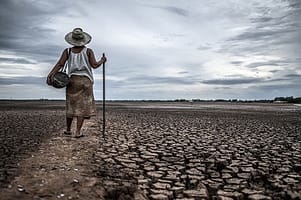 Women standing on dry soil and fishing gear, global warming and