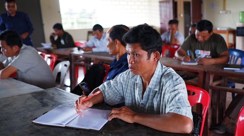 A farmer takes notes during the training in Dongbarkmai Village, Sanamsay District, capturing key information on red rice storage and sales. Photo: Lao Farmer Association