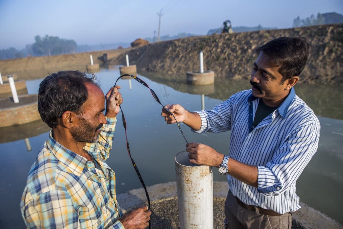 A scientist measuring the water collected from a pond created under the Underground Taming of Floods for irrigation (UTFI) Photo by Prashanth Vishwanathan / IWMI