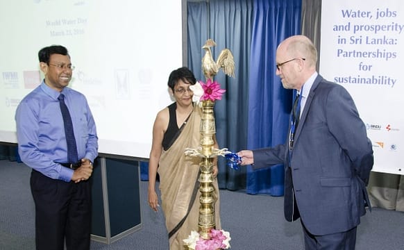 Dr Peter McCornick of IWMI lights the lamp at the start of the dialogue with Dr Ananda Mallawatantri of IUCN and Shyama Salgado of ILO