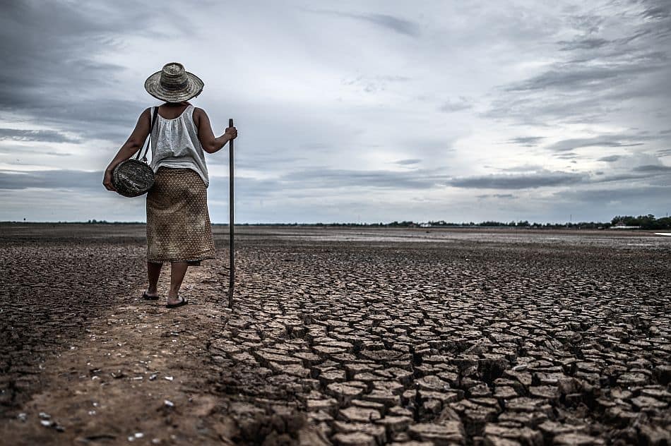Women standing on dry soil and fishing gear, global warming and
