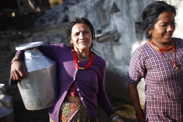 Since there is no running water inside the houses of Dhap, women carry water home in large jars from a nearby public water tap. Before water management started in Dhap village, there used to be long lines of people waiting their turn to collect or use the water tap. Photo: Tom van Cakenberghe / IWMI