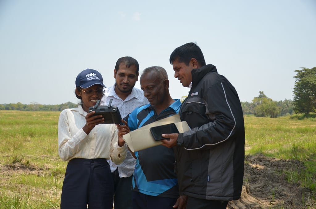 International Water Management Institute (IWMI) researchers Kalpani Jayamini and Lahiru Madushanka showing a farmers and an officer from the Department of Agrarian Development, data collected by a drone from a paddy field in Kurunegala, Sri Lanka on March 6, 2026. Photo: Hasti Sadri/IWMI