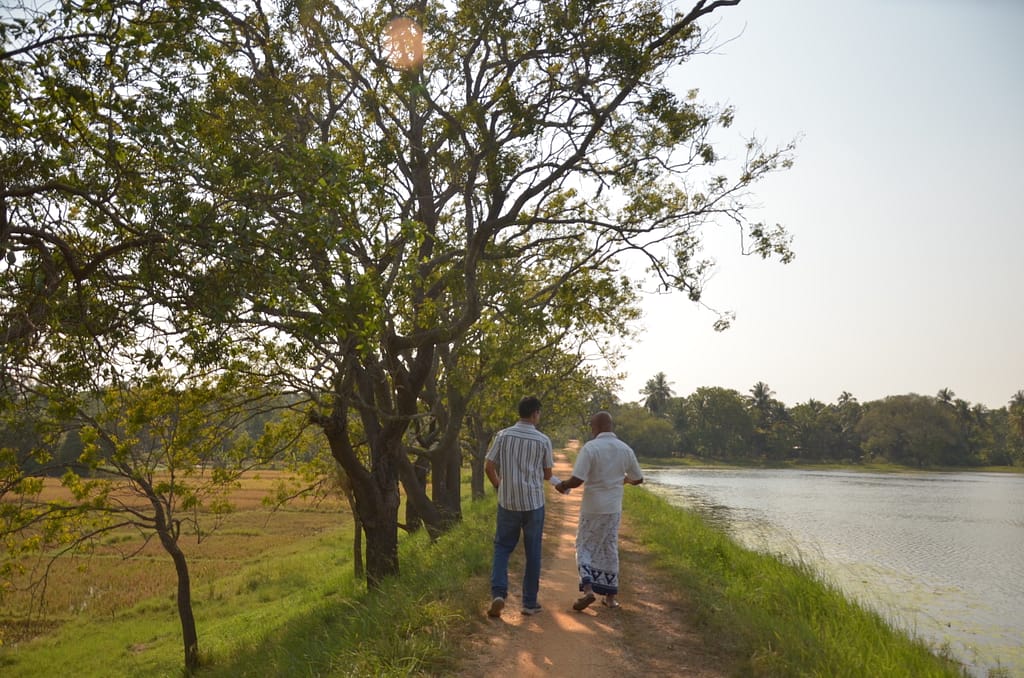 Researcher Group Leader at the International Water Management Institute (IWMI) Giriraj Amarnath walking alongside farmer H.U.D. Herath in Kurunegala, Sri Lanka, as they discuss the challenges paddy farmers face, on March 6, 2026. Photo: Hasti Sadri/IWMI
