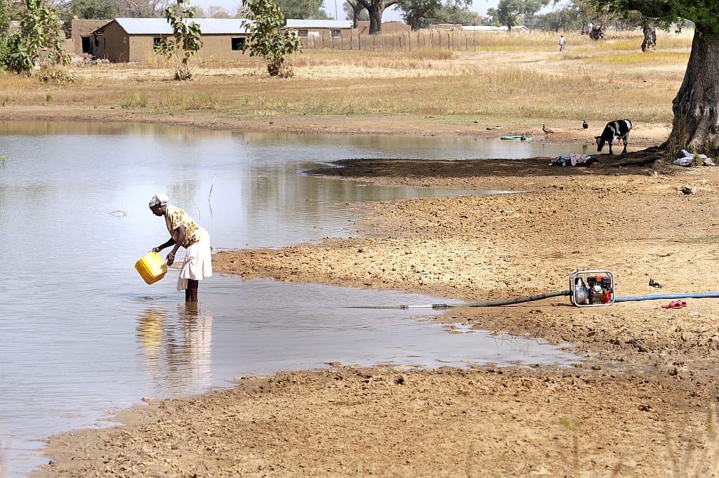 Woman fetching water from a small reservoir close to a pumping point-Hamish-John-Appleby