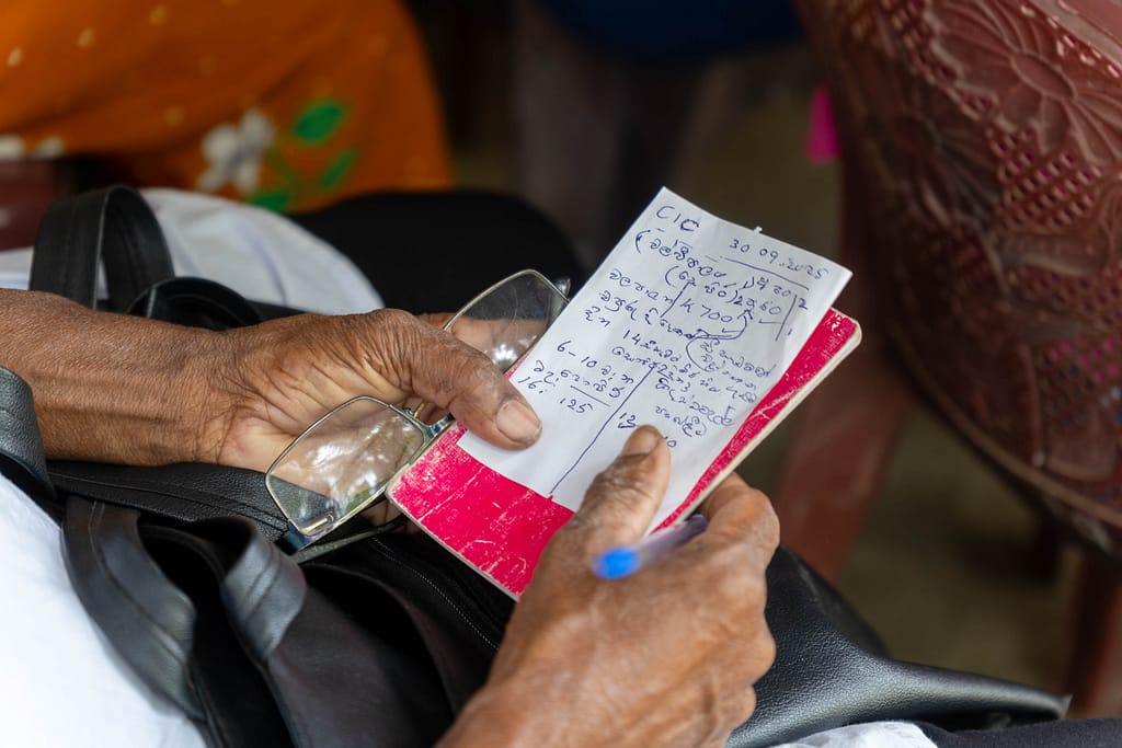 A farmer takes notes during the CIC Lanka officials brief farmers in Nagollagama, Kurunegala District, Sri Lanka, on drought management using high-yield, water-efficient seeds on September 30, 2025. Photo: Pradeep Liyanage/IWMI.
