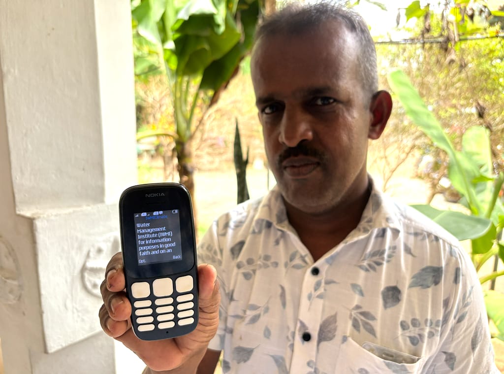 Farmer AM Ananda Ranjith Bandara showcasing a weather advisory from the International Water Management Institute on his phone in Kurunegala, Sri Lanka, on March 6, 2026. Photo: Samurdhi Perera/IWMI