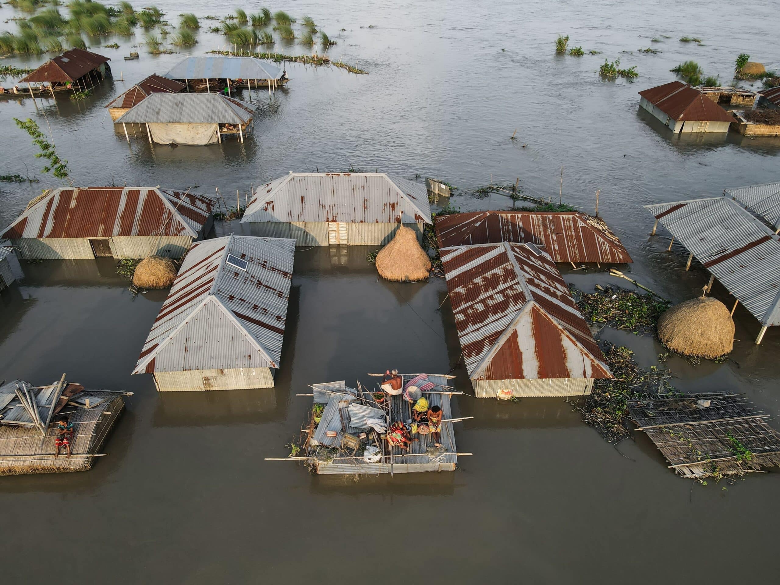 A family takes shelter on the roof of their house in Kurigram District, Bangladesh. Photo: Muhammad Amdad Hossain / Climate Visuals