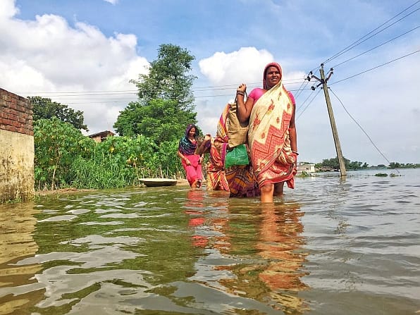 Residents along the banks of the river, wade through flooded streets.