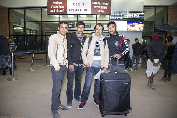 Migrant workers pose before departure. Tribhuvan International Airport in Kathmandu has a special working visa gate for migrants. Economic liberalization, rising costs of living in rural areas, climate stressors and globalization-induced cultural changes have increased the demand for cash, meaning that more and more young Nepalis are opting to work abroad. Photo: Sharad Maharjan