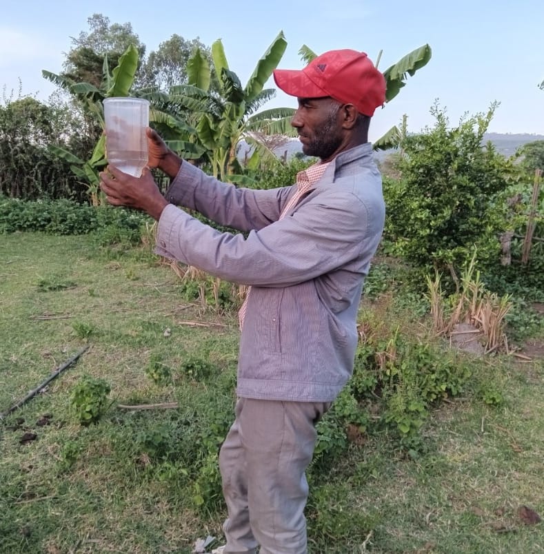 A citizen scientist reads rainfall data from a rain gauge before archiving it in his record book in South Sodo District of Ethiopia. Photo: Tilaye Worku / IWMI